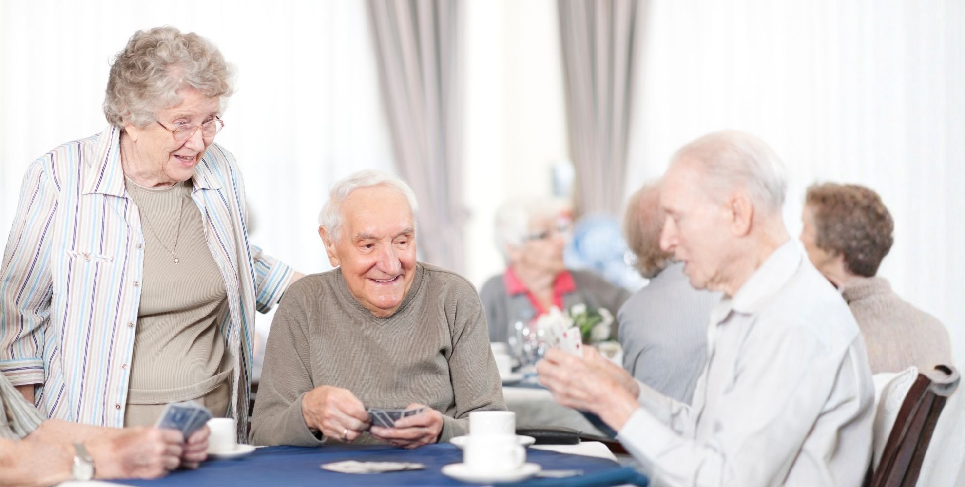 Group of seniors playing cards and drinking tea