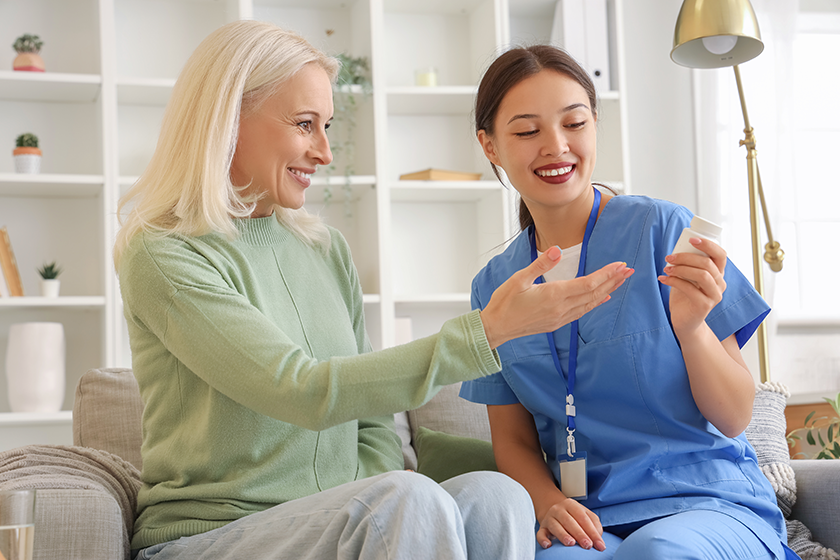 Female doctor showing pills to patient at home