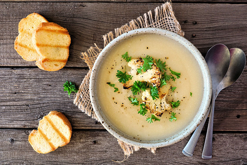 Roasted cauliflower and potato and soup. Top view table scene over a rustic wood background.